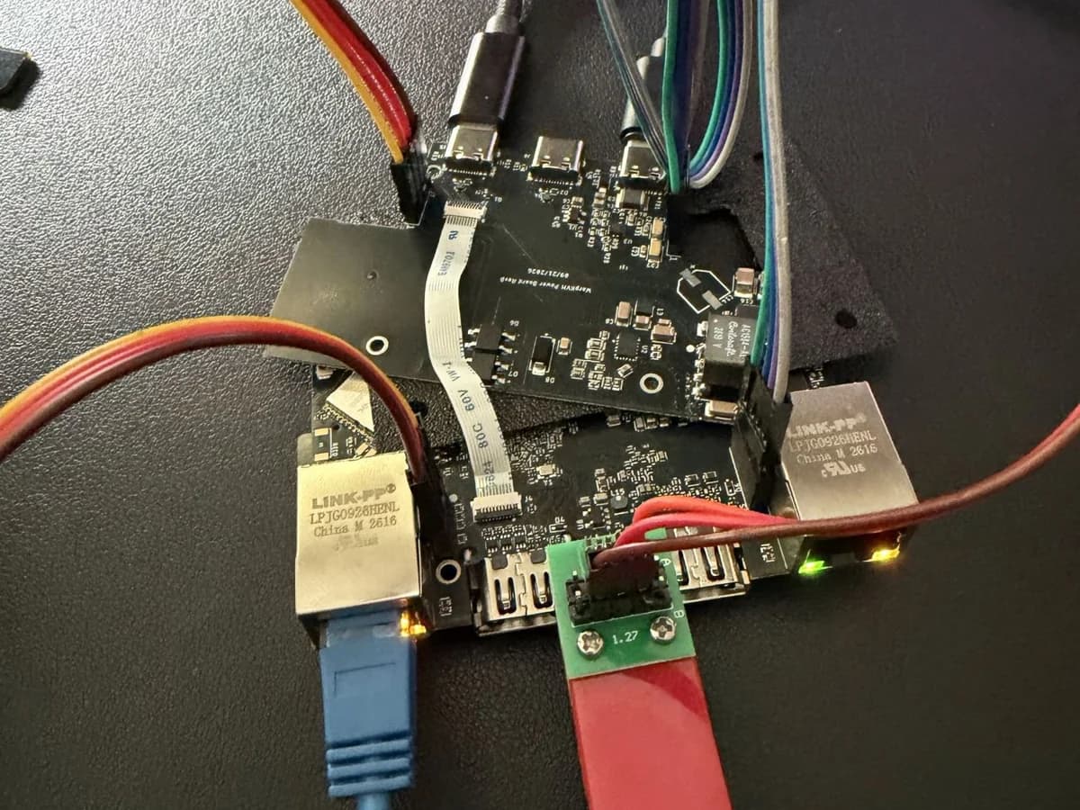WarpKVM 01 prototype on the bench with power board rev B, Ethernet connected with link LEDs lit, and a debug adapter on the 1.27 mm header.
