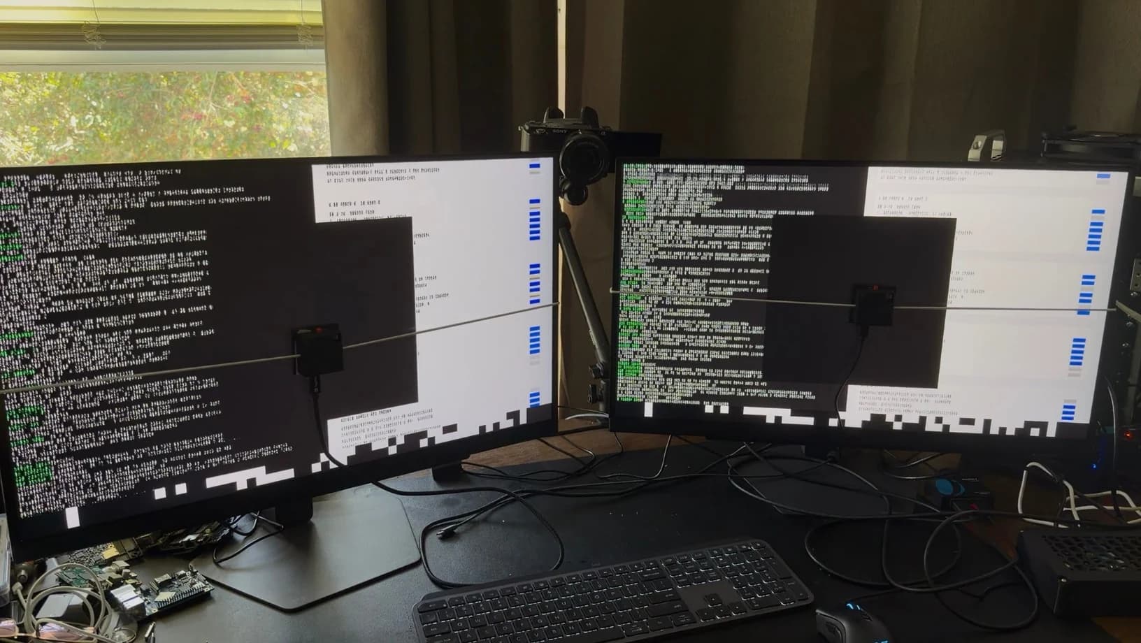 Glass-to-glass latency test rig: two matched monitors side by side, each with a light sensor hung in front of the screen.